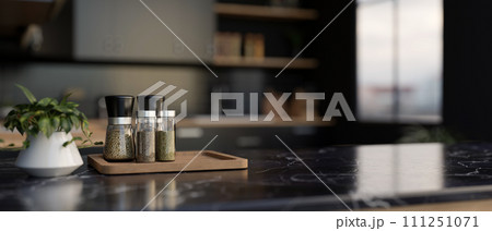 A set of spice bottles on a luxury black marble kitchen countertop in a modern black kitchen. 111251071