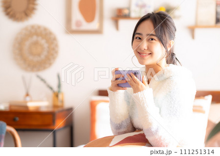 ベットでくつろいでスマホを見る大学生の女性 ベットでくつろいでスマホを見る大学生の女性 111251314
