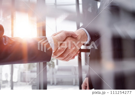 executives shaking hands in front of their manager and a colleague 111254277