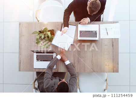 Two successful smiling businessmen are working on a laptop. view from above Two successful smiling businessmen are working on a laptop. view from above 111254459