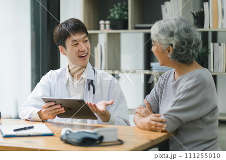 Young male doctor explaining diagnosis to senior woman patient about test results. Young male doctor explaining diagnosis to senior woman patient about test results. 111255010