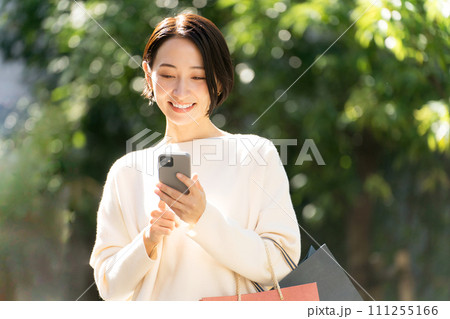 スマホを持つ買い物帰りの女性 スマホを持つ買い物帰りの女性 111255166