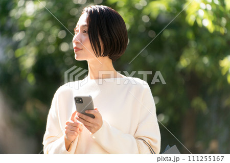 スマホを持つ買い物帰りの女性 スマホを持つ買い物帰りの女性 111255167