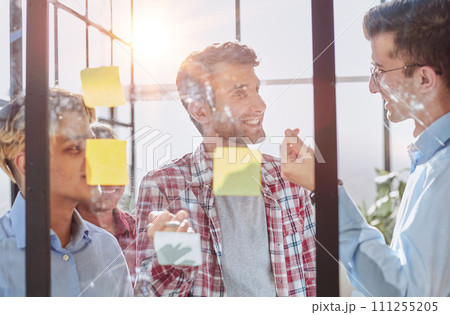 A group of business people behind a glass wall in the office sticking notes 111255205