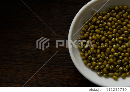 木目背景白いお皿に入った緑豆　もやしの種　ムング豆 111255750