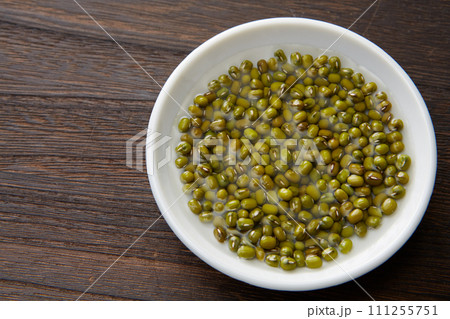 木目背景白いお皿に入った緑豆　もやしの種　ムング豆 111255751