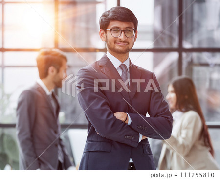 Handsome young business man in glasses standing confidently in the office Handsome young business man in glasses standing confidently in the office 111255810