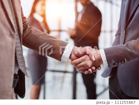 close-up of a handshake of business partners against the background of colleagues 111255867