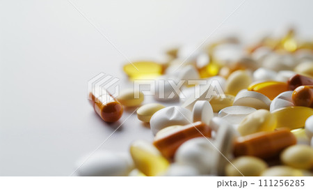 Colorful pills and capsules scattered on the table. Minimal medical concept. Flat lay, top view on light gray background 111256285