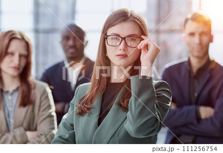 Portrait of a young serious business woman with colleagues 111256754