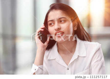 Portrait of young business woman with glasses ofand talking on mobile phone Portrait of young business woman with glasses ofand talking on mobile phone 111257117
