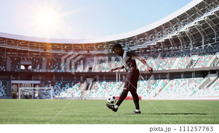 African American man playing football on the stadium field. A man runs with a soccer ball across the field. African American man playing football on the stadium field. A man runs with a soccer ball across the field. 111257763