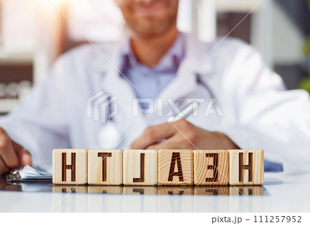 the doctor folded the word healthy from wooden cubes on the table in the hospital the doctor folded the word healthy from wooden cubes on the table in the hospital 111257952