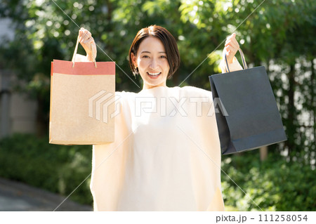 ショッピングバッグを両手に持つ女性 111258054