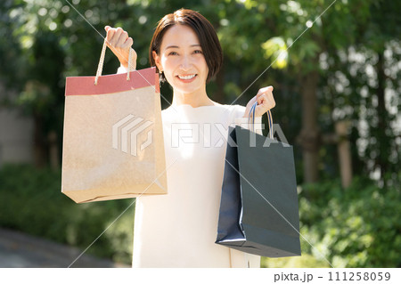 ショッピングバッグを両手に持つ女性 111258059