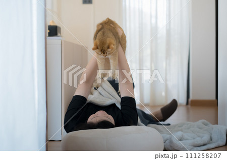wellness and wellbeing concept with asian woman lie down and read book and play with her cat in livingroom wellness and wellbeing concept with asian woman lie down and read book and play with her cat in livingroom 111258207