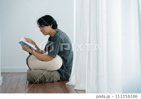 wellness and wellbeing concept with asian man sit and relax and read in livingroom 111258286