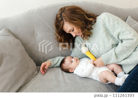 Happy mother resting on sofa with baby Happy mother resting on sofa with baby 111261305
