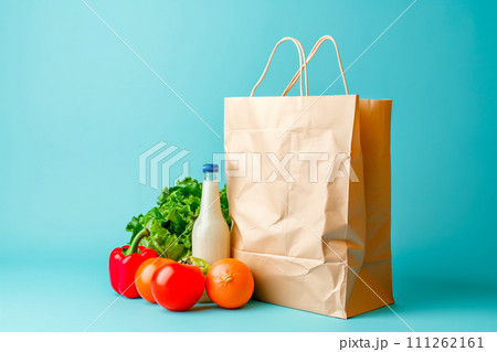 Craft brown shopping paper bag and grocery on blue background. Delivery concept Craft brown shopping paper bag and grocery on blue background. Delivery concept 111262161