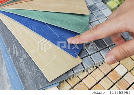 designer's hand choosing samples of interior stone material consists concrete tiles, quartz stones, artificial stones, graphic tile. designer's hand choosing samples of interior stone material consists concrete tiles, quartz stones, artificial stones, graphic tile. 111262963