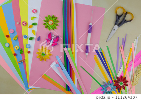 Table with multi colored paper and tools for rolling paper using the quilling technique. Hobby for developing fine motor skills 111264307