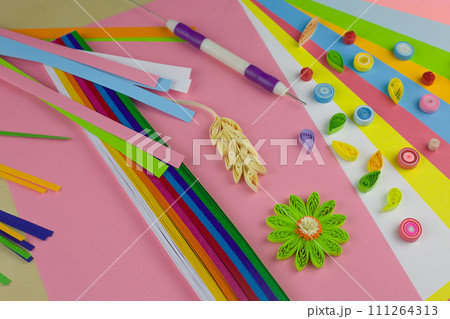 Table with colored paper for twisting ribbons into beautiful details for decoration. Quilling paper and tools Table with colored paper for twisting ribbons into beautiful details for decoration. Quilling paper and tools 111264313