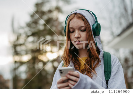 Portrait of teenage girl looking at her smartphone, sad, anxious, alone. Cyberbullying, girl is harassed, threated online. 111264900