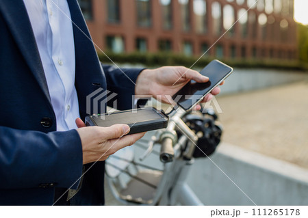 Businessman, freelancer or manager working outdoors in city park. Charging smartphone with solar phone charger. Concept of working remotely. 111265178