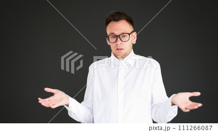 Uncertain shrug. No idea. Doubt ignorance. Clueless overwhelmed careless smart guy raising shoulders isolated on dark black empty space background. 111266087