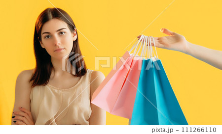 Shopaholic control. Reject offer. Dislike shopping. Woman customer refusing to receive shopping bags from female hand isolated on orange background. Shopaholic control. Reject offer. Dislike shopping. Woman customer refusing to receive shopping bags from female hand isolated on orange background. 111266110