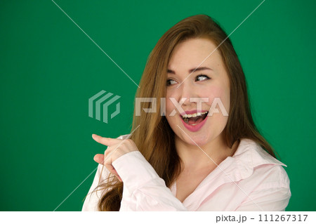 woman advertises something at mock-up blank white copy space on side up background pointing indicates with index finger 111267317