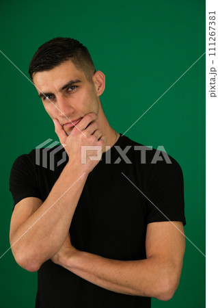 young guy lost in thought, supports his head with his hand, squints his eyes, gazes intently, black T-shirt, light stubble, macho, ponders thoughts, emotions of a handsome man young guy lost in thought, supports his head with his hand, squints his eyes, gazes intently, black T-shirt, light stubble, macho, ponders thoughts, emotions of a handsome man 111267381