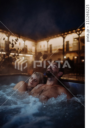 Beautiful mature couple relaxing in outdoor hot tub, enjoying romantic wellness weekend in spa. Concept of Valentine's Day. Beautiful mature couple relaxing in outdoor hot tub, enjoying romantic wellness weekend in spa. Concept of Valentine's Day. 111268225