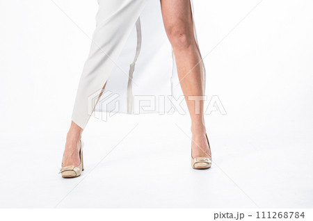 Legs of a slender young woman in a dress on a white background. Sexy, high heels and woman with dress and legs posing as beauty model. Legs of a slender young woman in a dress on a white background. Sexy, high heels and woman with dress and legs posing as beauty model. 111268784