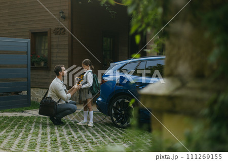 Father handing girl her science project for school science fair, robotic arm. Electric car is charging before going to school and work. Concept of young girls in science. Father handing girl her science project for school science fair, robotic arm. Electric car is charging before going to school and work. Concept of young girls in science. 111269155