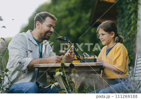 Father supporting daughter in pursuing robotics, science, IT technologies and programming. Concept of young girls in science. 111269188