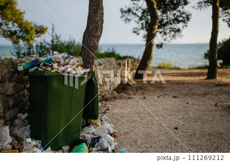 Trash in the street spilling on to the pavement. Full bins in holiday destinations. 111269212