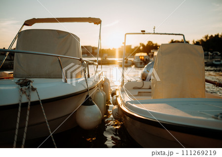 Small boats on calm water, moored in the harbor during sunset. 111269219