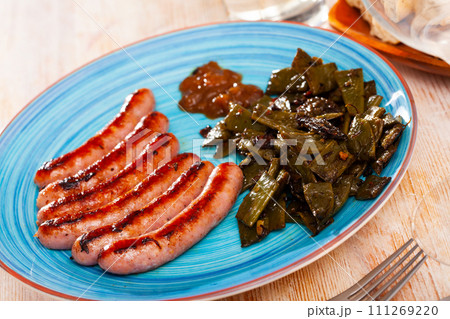 Tasty fried meat sausages served with stewed green beans Tasty fried meat sausages served with stewed green beans 111269220