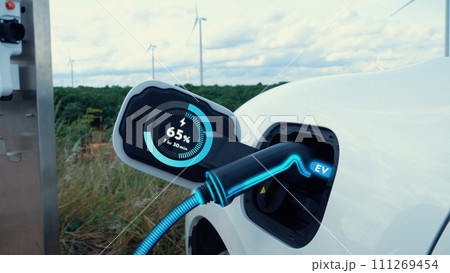 Electric car recharging energy from charging station in wind turbine farm.Peruse 111269454