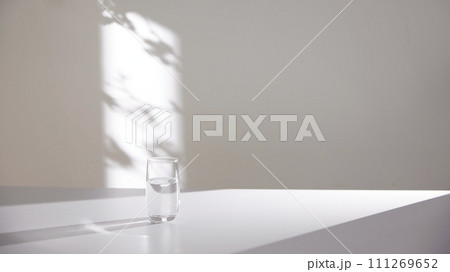 A water cup and shadow on a table in the sunlight. A water cup and shadow on a table in the sunlight. 111269652