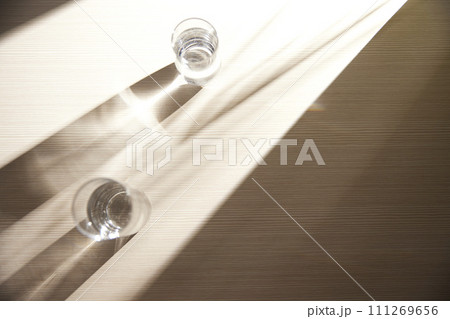 A water cup and shadow on a table in the sunlight. A water cup and shadow on a table in the sunlight. 111269656