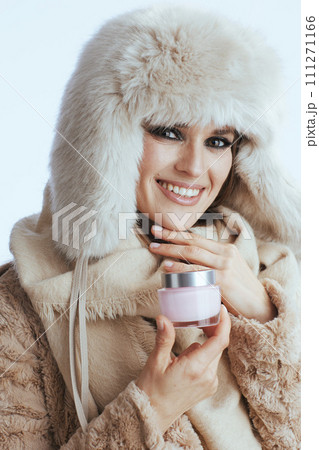 smiling stylish woman in winter coat and fur hat on white 111271166