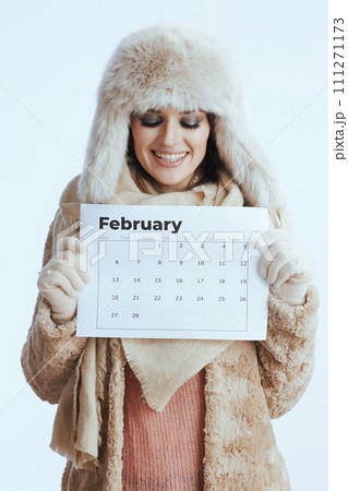 smiling woman in winter coat and fur hat on white 111271173