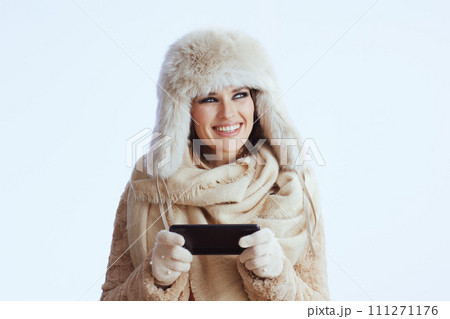 happy modern woman in winter coat and fur hat on white 111271176