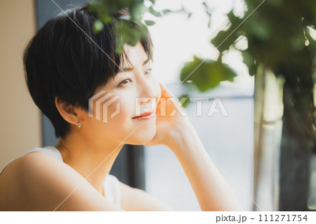 窓辺で夕陽を見る女性　 111271754