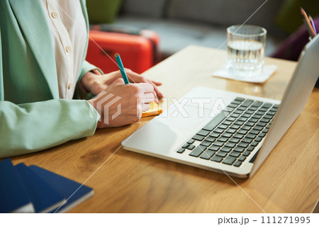 Cropped image. Focus on female hands making notes about hotel and tours. Planning vacation with online services, choosing trips and accommodation Cropped image. Focus on female hands making notes about hotel and tours. Planning vacation with online services, choosing trips and accommodation 111271995