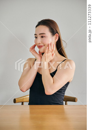 顔をマッサージして肌のお手入れをする30代女性 111273339