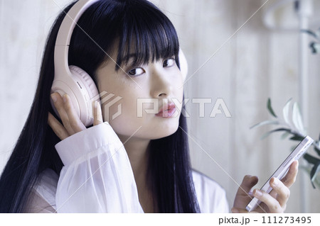 ヘッドホンでスマホの音楽を聴く若い女性 111273495