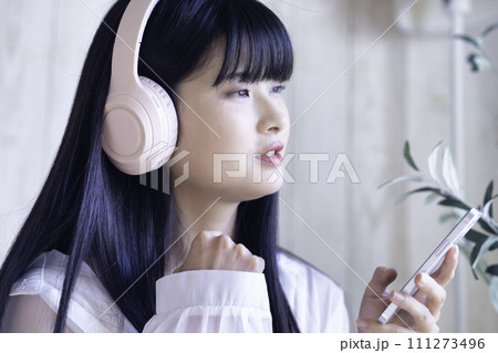 ヘッドホンでスマホの音楽を聴く若い女性 111273496